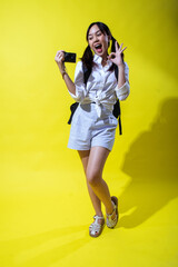 An Asian woman with pigtails, holding a camera in one hand while making an 