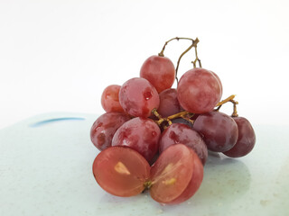 red grapes on a wooden plate and on a cutting board on a white background