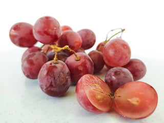 red grapes on a wooden plate and on a cutting board on a white background