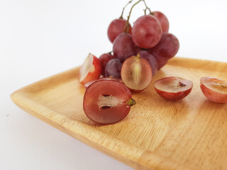 red grapes on a wooden plate and on a cutting board on a white background
