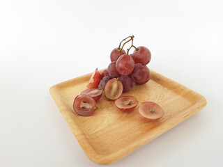 red grapes on a wooden plate and on a cutting board on a white background