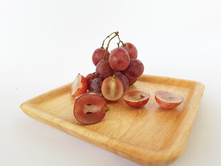 red grapes on a wooden plate and on a cutting board on a white background