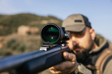 Obraz premium Hunter aiming with rifle scope in nature