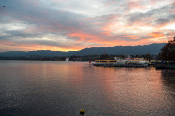 Tourist Ferry boat with light strings decoration docked at the pier on lake Zurich, Switzerland. Late autumn evening, no people