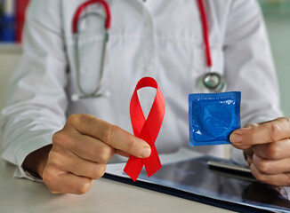 Doctor shows condom and red ribbon for World AIDS day in hospital HIV spreading problem awareness....