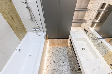 interior apartment Modern bathroom with wood and grey accents.  Features a sleek bathtub, glass...