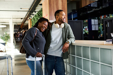 A happy couple relaxes in a lively hotel lobby, excited for their vacation adventures ahead.
