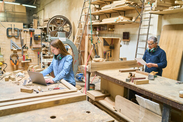Young apprentice working alongside mentor in a busy lumberyard