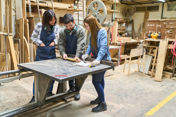 Young apprentices collaborating in a busy lumberyard workshop