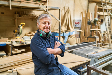 Experienced craftsman confidently posing in a woodworking shop