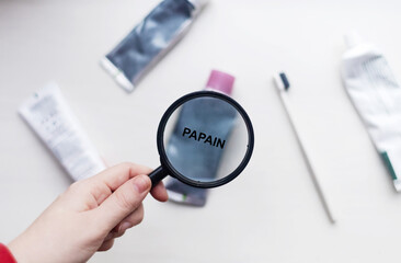 Papain in natural toothpaste. Magnifying glass is directed at a tube with a list of ingredients of a safe product. Safe toothpaste composition