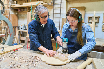 Mentor guiding apprentice in woodworking crafts and techniques
