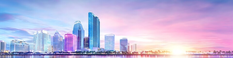 Obraz premium A vibrant cityscape of Florida at dusk, showcasing the iconic landmark with high-rise buildings . The sky is painted with hues of blue and purple as the sun sets behind them, casting long shadows on