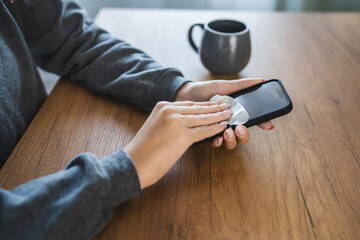 woman clean a smart phone screen of dust with a cleaning wipe indoor