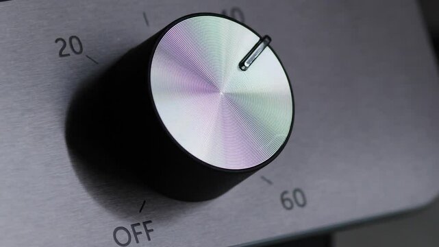 close up of female hand turning round switch to on position on electric oven, mode switch or timer on electric kitchen stove, woman cooking food