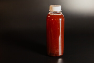 transparent bottle with red fruit drink on black background