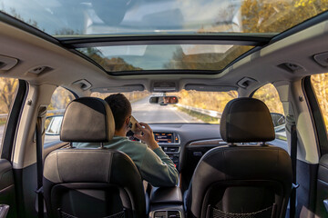 A young man drives a car. A young man drives a car and talks on the phone.