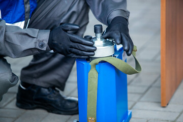 На фотографии работник в синем костюме работает руками на заводе или большом предприятии опустив голову на низ