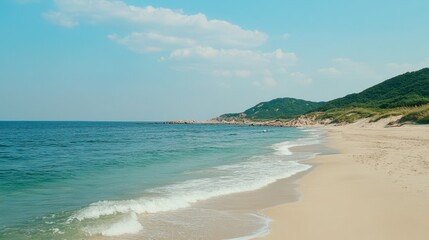 Fototapeta premium Scenic Beach Landscape with Gentle Waves and Lush Green Hills Under a Clear Blue Sky on a Calm Sunny Day