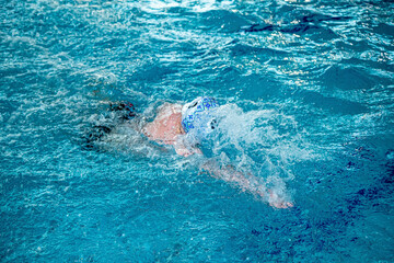 На фотографии изображены дети которые тренируются водным поло в большом и светлом бассейне.  мячь