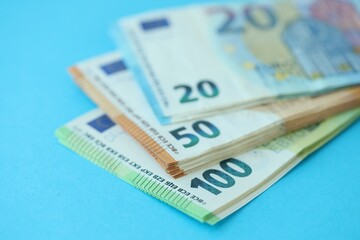 Big amount of one hundred, twenty and fifty euro money bills on blue background