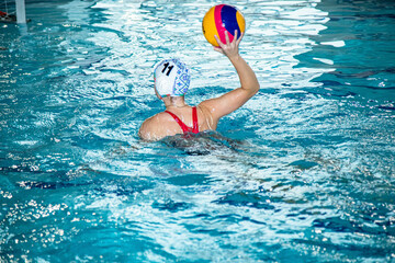 На фотографии изображены  как дети которые тренируются водным поло в большом и светлом бассейне.