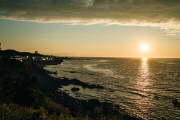 After a rainy day, fiery sunset over the St Lawrence river at the Pointe au Pere Lighthouse in Rimouski, Quebec