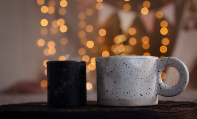 New Year's decor. Ceramic cup and candle on blurred bokeh background. Close-up. Copyspace