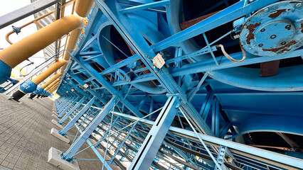 На фотографии современный вентилятор синего цвета с желтым цветом детали на нем  для охлаждения оборудование на открытом воздухе .