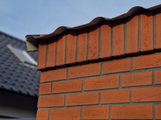 roof fence brick wall with clogged gutter leaves from tree. hard fired face tiles
