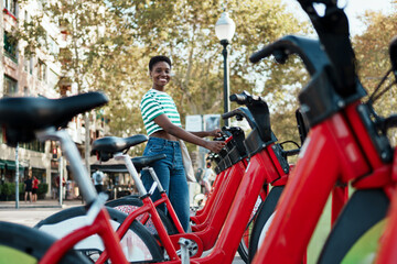 African American young woman using an mobile app to rent a shared bicycle 