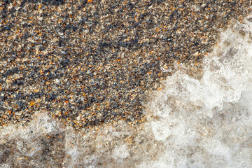 Sea water foam on crushed sea shells ans sand, soft focus close up with motion blur