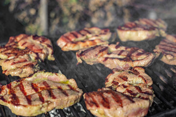 Pork neck, pork collar slices marinated, grilling with smoke outside, soft focus close up side view