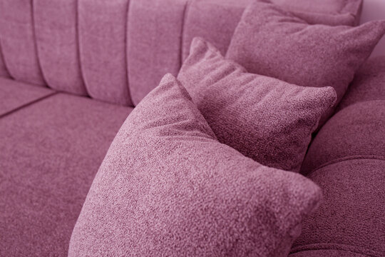 Pink couch detail with three pillows, cloae up