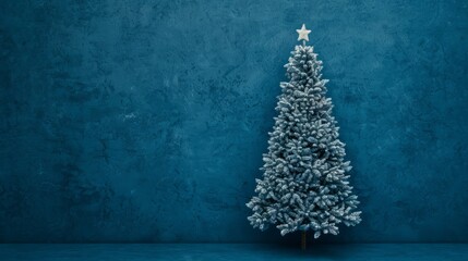 Snowy Christmas tree against a blue wall backdrop.