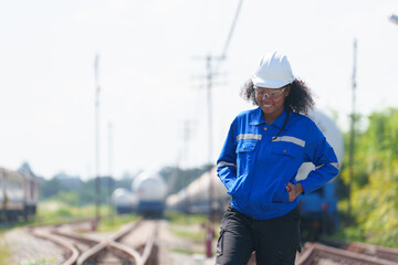 A black female engineer walks the tracks inspecting the readiness of a gas-powered train.