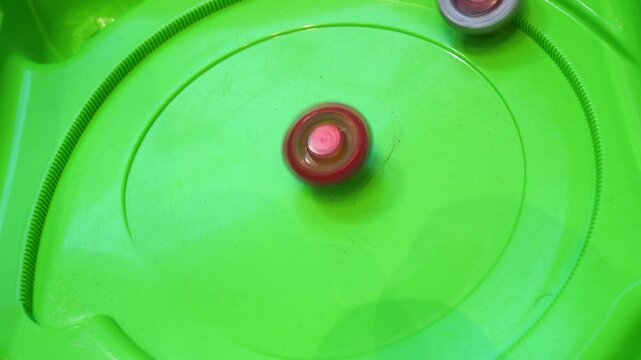 Popular and trendy boy beyblade spinning toy match and battle. Green elements of battle arena for beyblades in slow motion