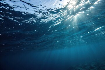 Dark blue ocean surface viewed from an angle with sunlight filtering down through the water, light penetration, oceanic gradient, refracted light, underwater illumination