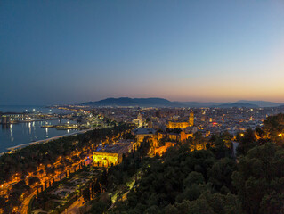 A stunning night view of Málaga from the Atalaya, showcasing the glowing bullring, city lights, and serene sea. Ideal for urban, travel, and cultural visuals.
