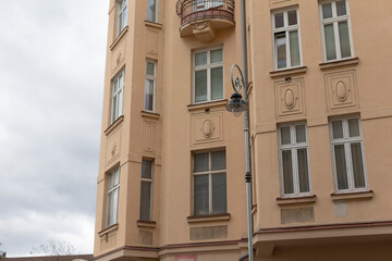 Fototapeta premium An elegant yellow apartment building stands as a stunning example of unique architecture, beautifully incorporating urban elements such as a charming balcony and a decorative street lamp