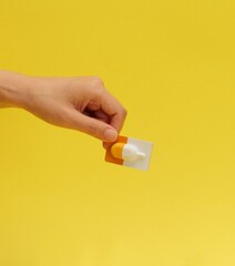 A woman holding cosmetics and a yellow background