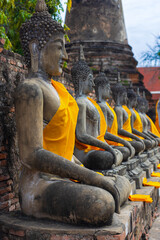 Row of old seated Buddha statues in golden robe at Wat Yai Chai Mongkol in Ayutthaya, Thailand