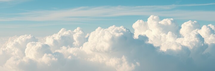 Vast cumulus clouds drift across a bright blue sky at midday
