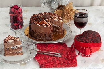 Cocoa cake and a glass of cola on a table. Next to it is a red heart-shaped gift box.