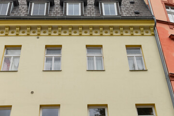 The facade of a beautifully designed yellow building showcases exquisite decorative architectural details and an array of multiple windows, enhancing the charm and character of the urban landscape