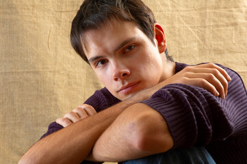 Guy with crossed arms on beige background close up