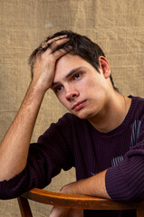 Young thoughtful brunette on an old chair on a crumpled fabric background