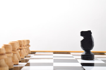 Chess Knight in front of enemy pawns on chess board on white background © Mulad Images