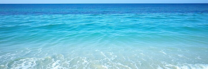 Obraz premium A tranquil ocean scene with gentle lapping waves and a soft blue ocean surface reflecting the clear blue sky above, ocean scenery, serene landscape, turquoise ocean