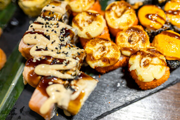 Colorful sushi platter featuring various rolls and toppings served on a black slate at a restaurant during dinner